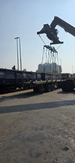 Material handler lifting jumbo bags alongside rail wagons